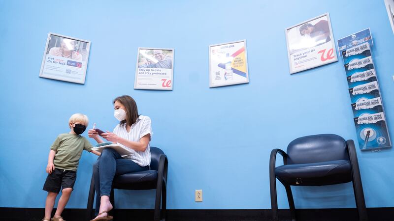 Three year-old Fletcher Pack watches as his mother, McKenzie Pack, fills out paperwork prior...