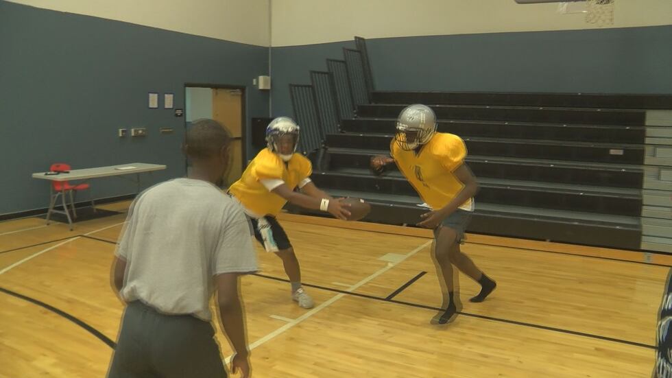 Quarterback hands the ball of to the running back during a football practice